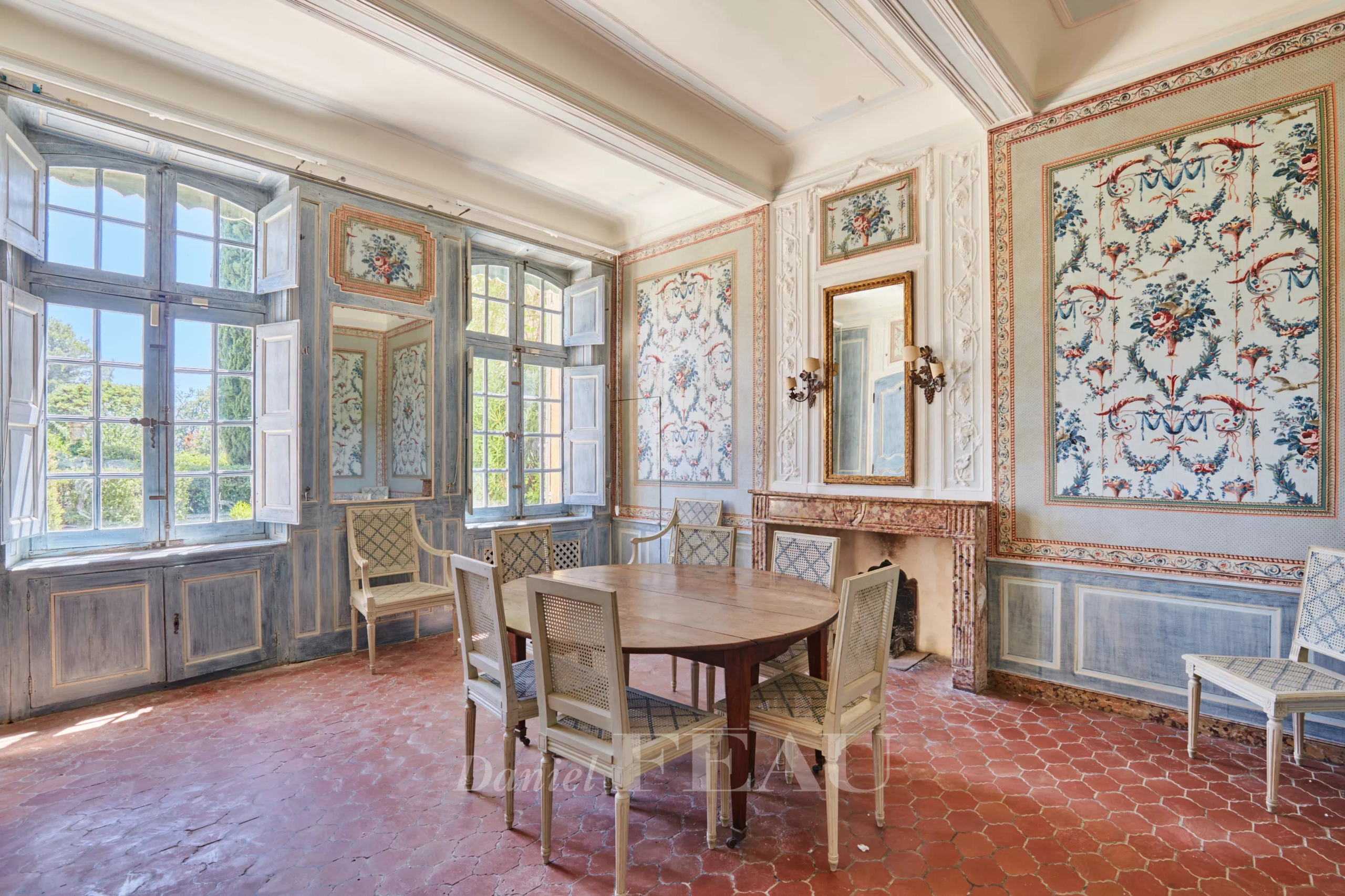 Intérieur d'une bastide du XVIIIème siècle avec des murs décorés et une grande table ronde.