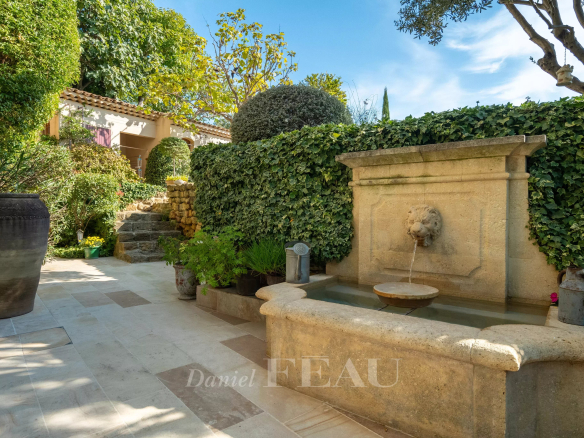 Garden with stone fountain and lush vegetation, restored old presbytery.