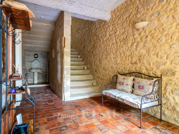 Interior of an old stone presbytery with a staircase and a bench, exposed stone walls.