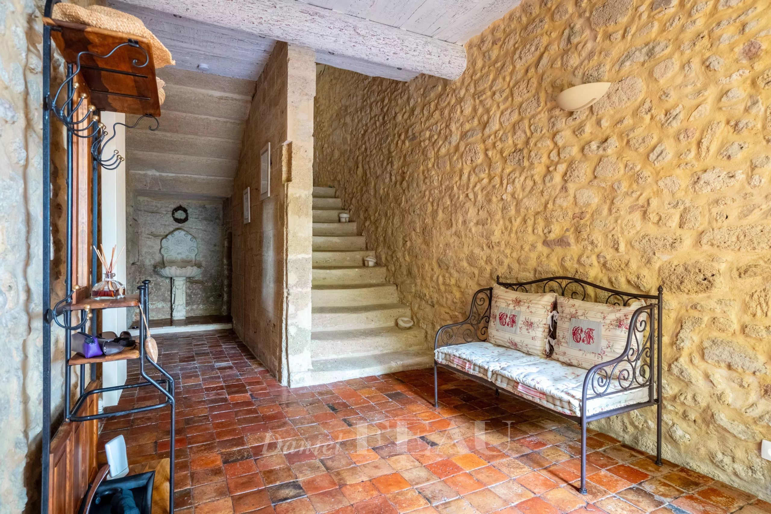 Interior of an old stone rectory Interior of an old stone presbytery with a staircase and a bench, exposed stone walls.
