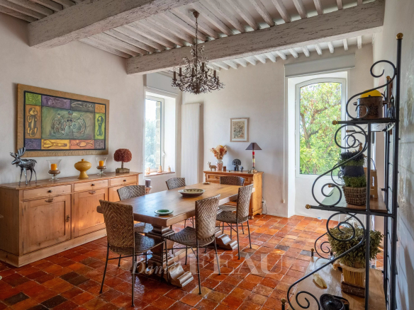 Dining room of a former 18th-century stone presbytery with wooden furniture and terracotta tiles.