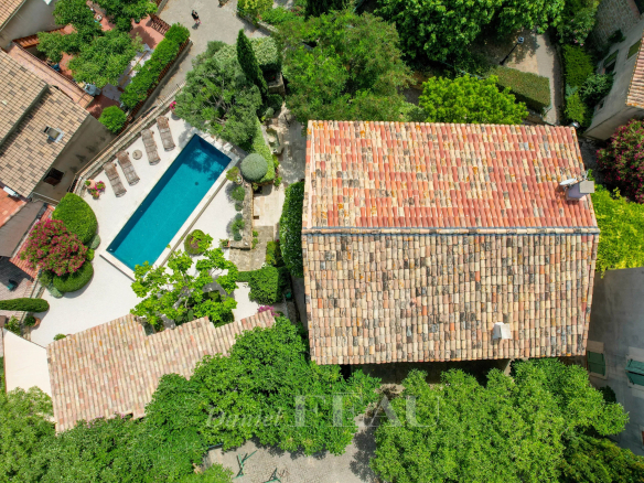 Aerial view of a stone house with a swimming pool, surrounded by greenery, between Aix-en-Provence and Saint-Rémy.
