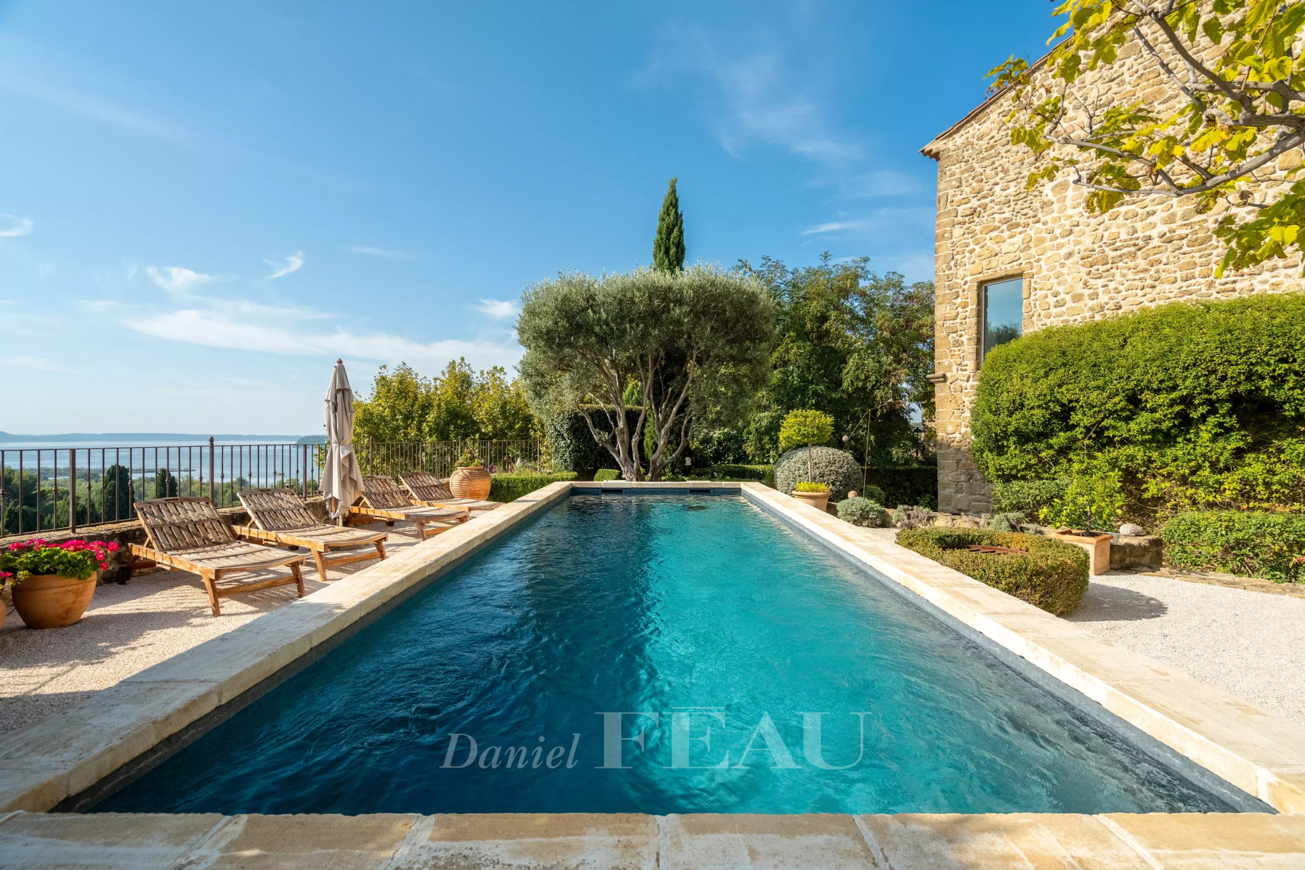 Swimming pool of a stone house Swimming pool surrounded by greenery and sun loungers, with an unobstructed view of nature.