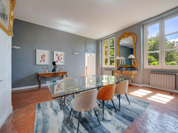 Dining room of an apartment in Aix-en-Provence with a glass table and colorful chairs.