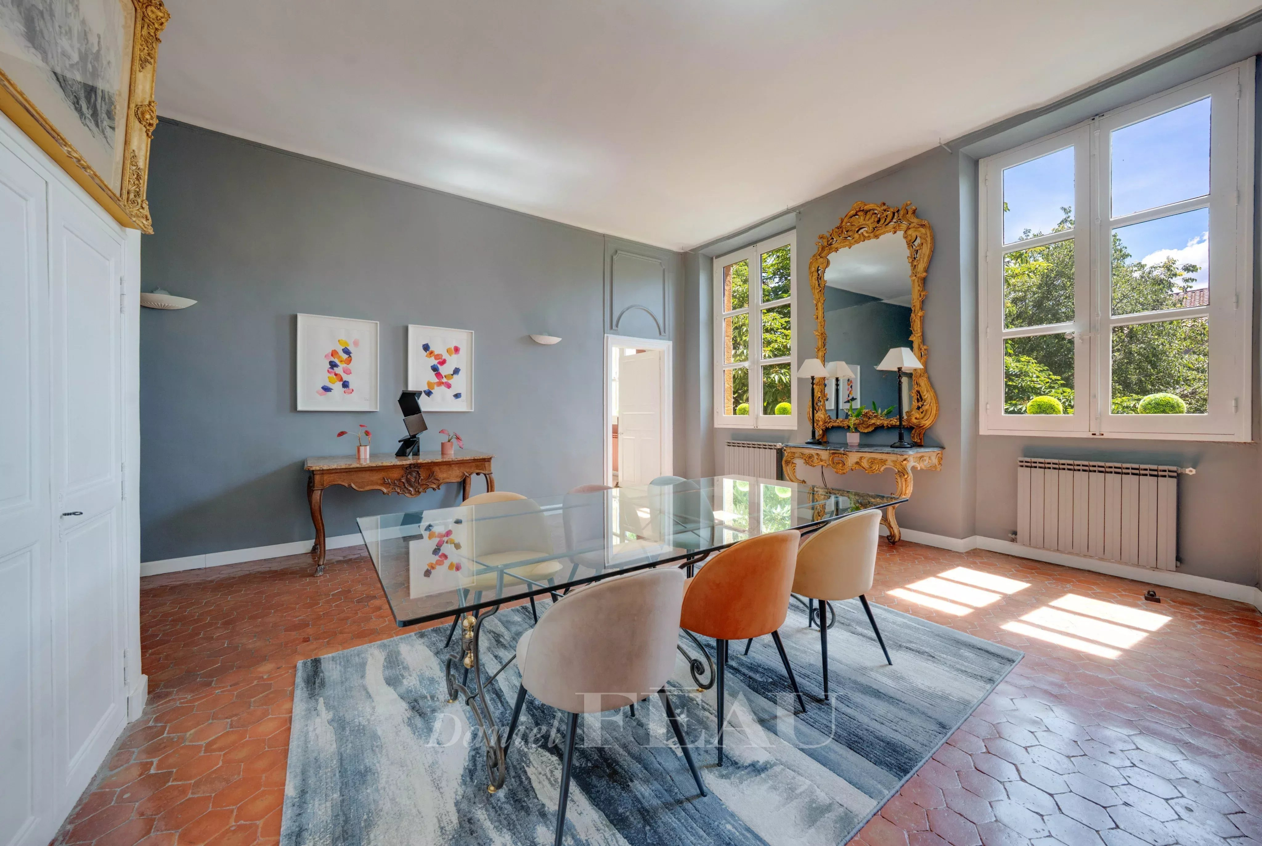 Salle à manger d’un appartement à Aix-en-Provence Salle à manger d'un appartement à Aix-en-Provence avec table en verre et chaises colorées.