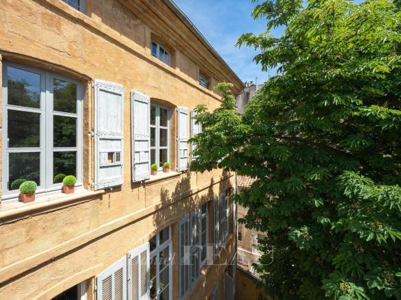 Façade d'un appartement à Aix-en-Provence avec fenêtres à volets et verdure environnante.