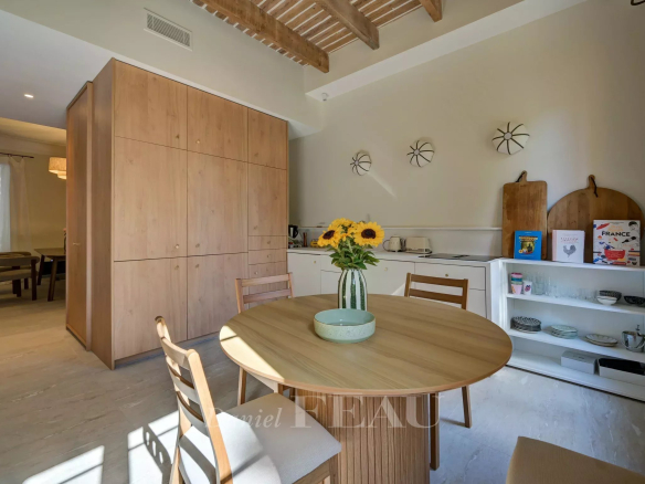Interior of a modern apartment with a round table, chairs and an open kitchen.