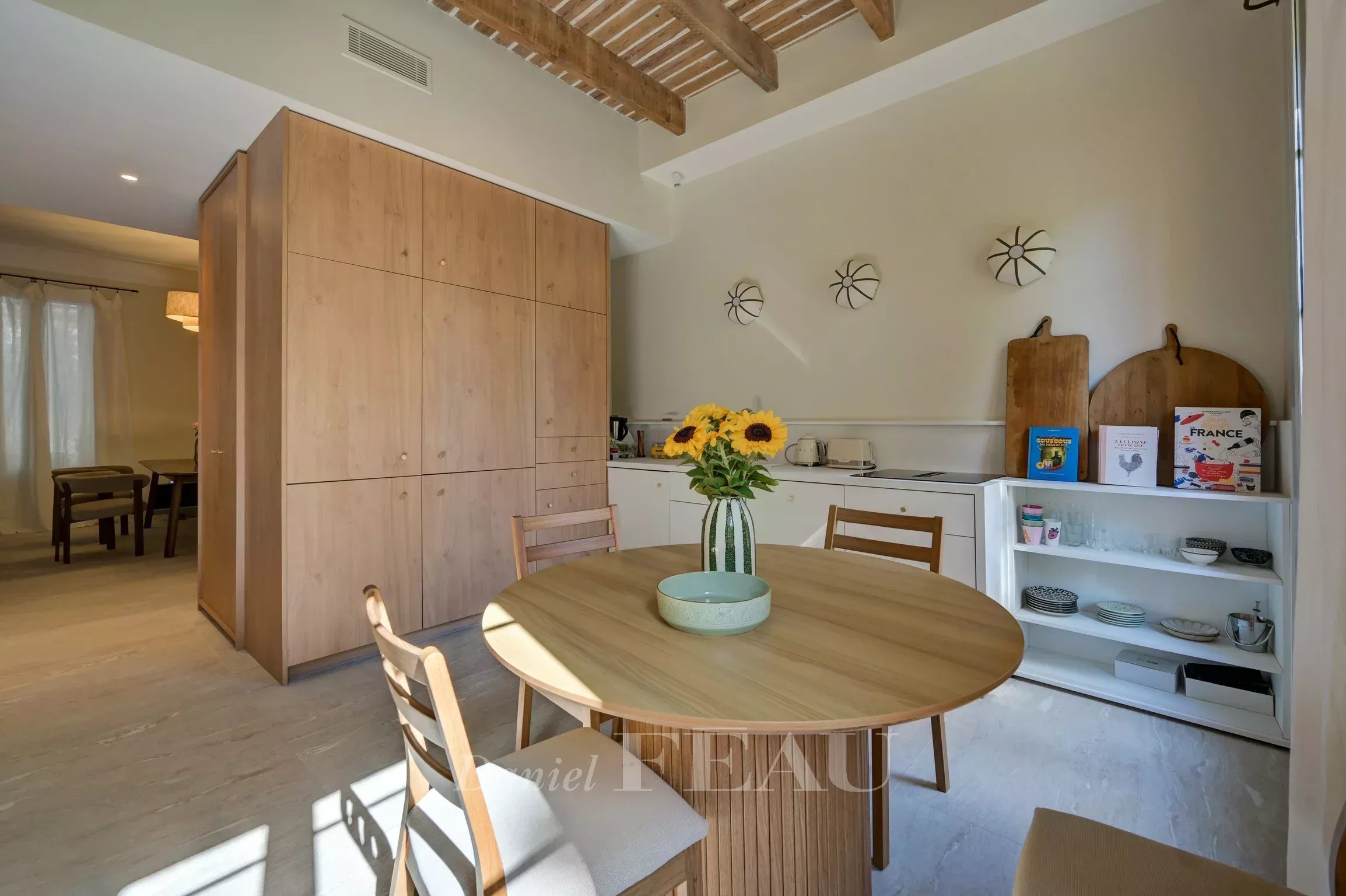 Renovated apartment in Aix-en-Provence Interior of a modern apartment with a round table, chairs and an open kitchen.
