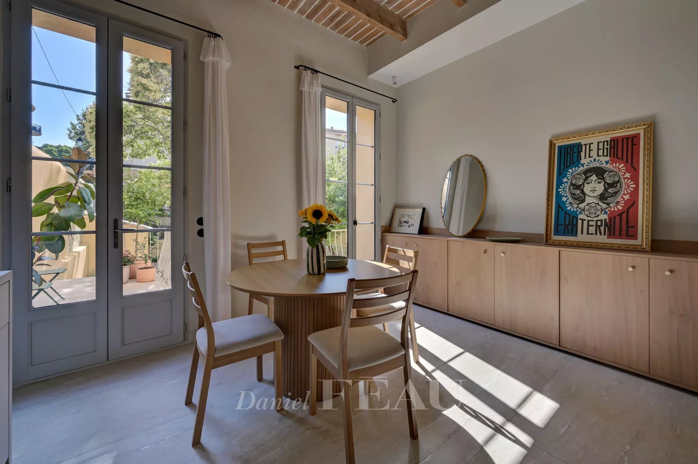 Apartment in Aix-en-Provence Interior of an apartment in Aix-en-Provence with a round table, chairs and windows opening onto the garden.