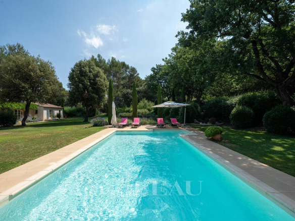Piscine entourée de chaises longues dans un parc paysager à Aix-en-Provence.