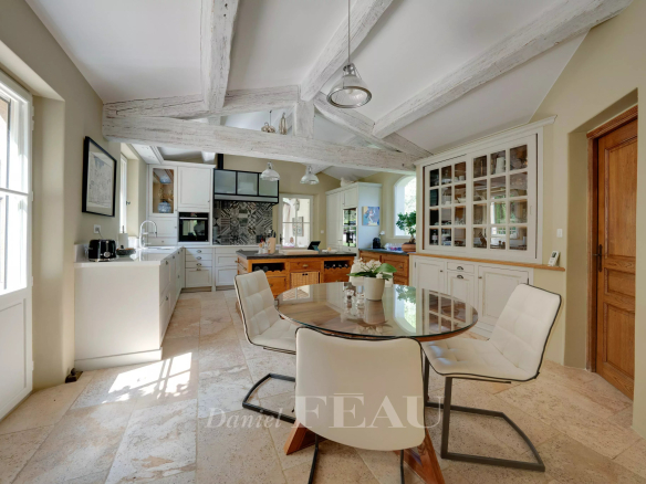 Intérieur d'une cuisine élégante avec table ronde et chaises blanches, lumière naturelle.