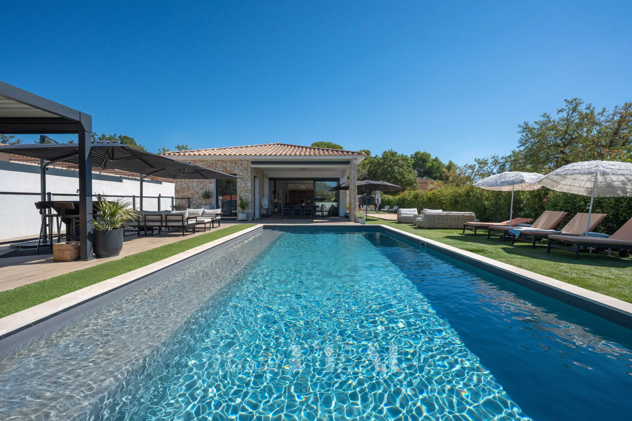 Maison contemporaine à Aix-en-Provence Maison contemporaine avec piscine à Aix-en-Provence, vue sur le jardin et parasols.