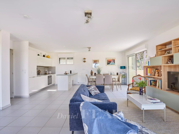 Intérieur d'un appartement moderne avec salon, cuisine ouverte et accès à une terrasse.