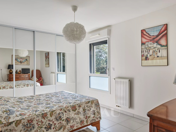 Chambre d'appartement avec lit, armoire et fenêtre donnant sur l'extérieur.