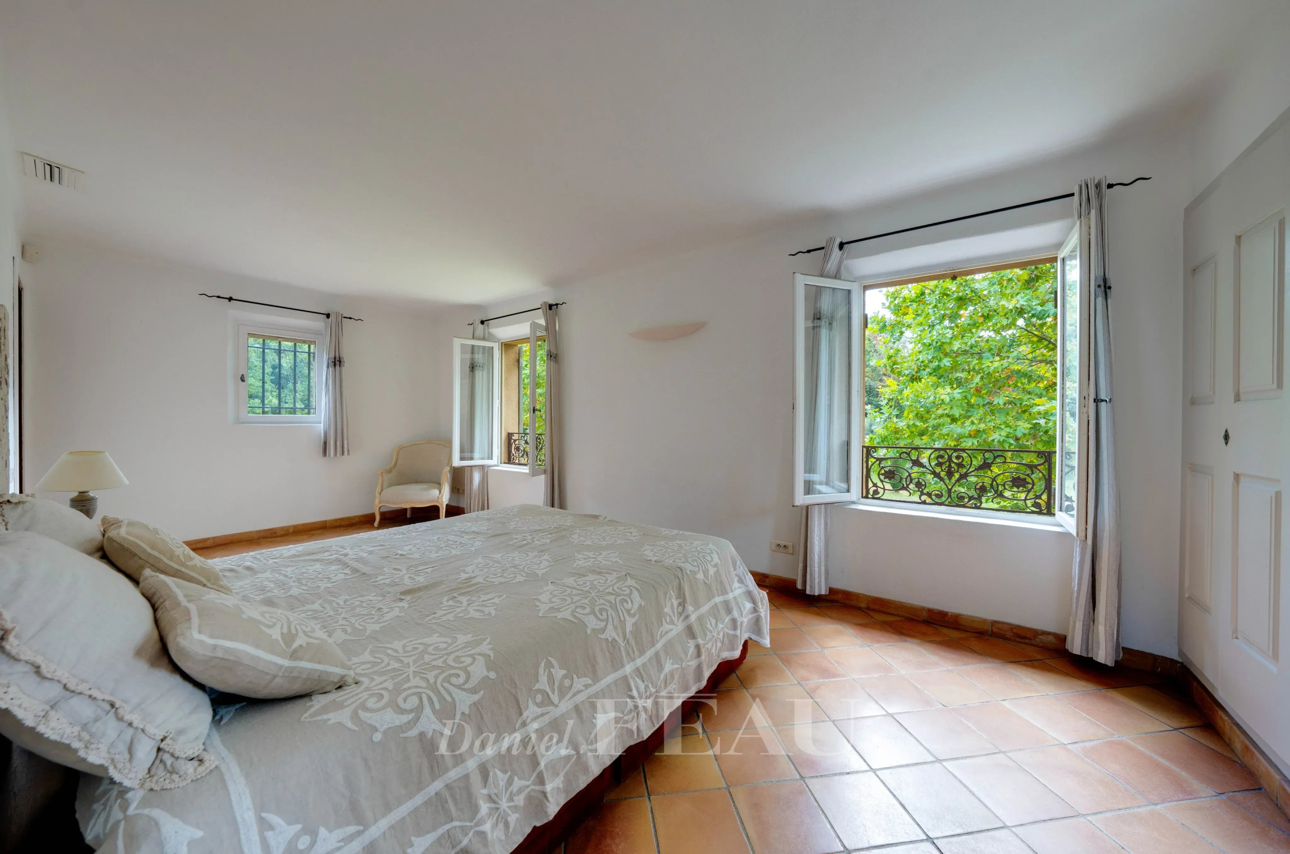 Chambre spacieuse avec fenêtres ouvertes sur un parc verdoyant, à Aix-en-Provence.