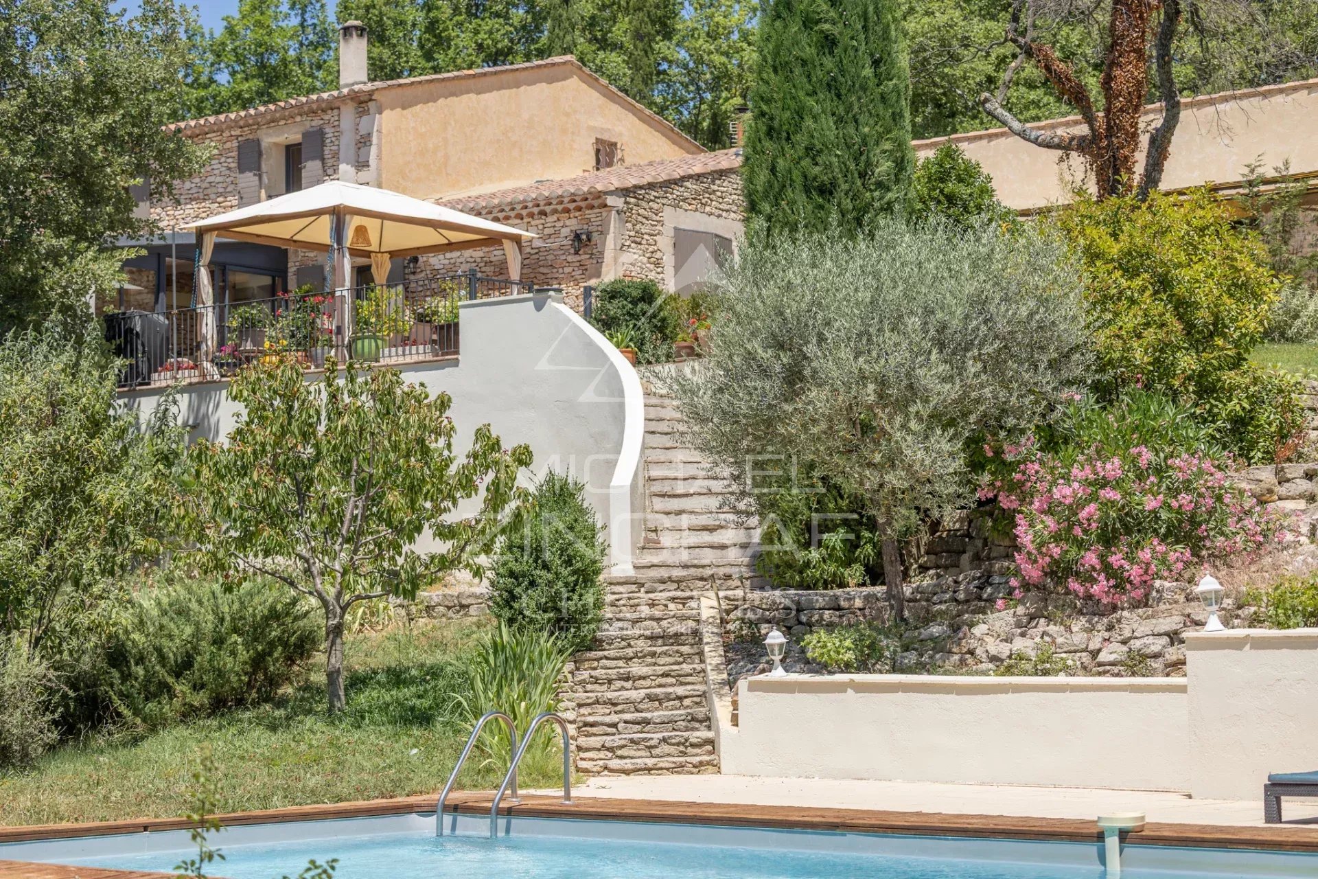 Property with swimming pool and outbuildings in Gordes, Luberon, surrounded by a wooded park.