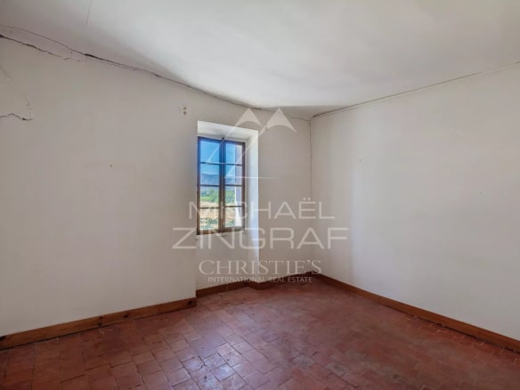 Intérieur d'un mas XVIIIe à rénover, avec une fenêtre donnant sur un paysage de campagne.