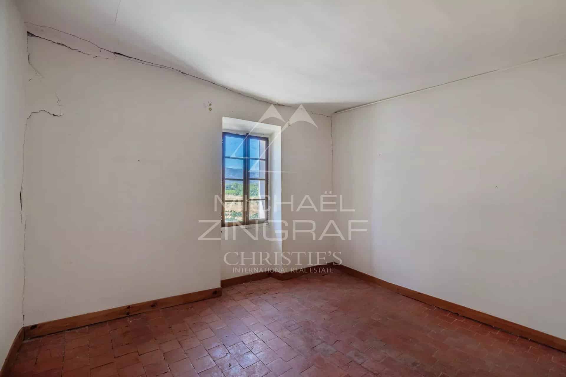 Intérieur d'un mas XVIIIe à rénover, avec une fenêtre donnant sur un paysage de campagne.