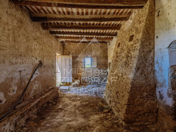 Intérieur d'un mas XVIIIe à rénover avec murs en pierre et poutres apparentes.
