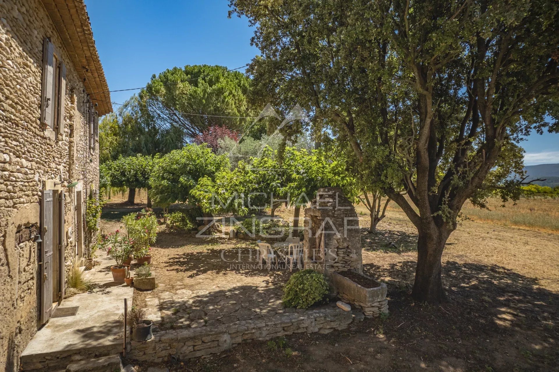 Mas XVIIIe authentique à rénover avec vue sur le Luberon, entouré d'arbres et de verdure.