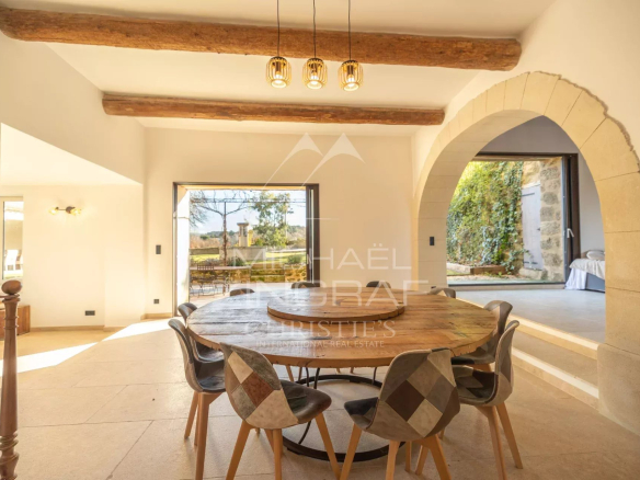 Interior of a renovated farmhouse with a large wooden table and chairs, bathed in light.