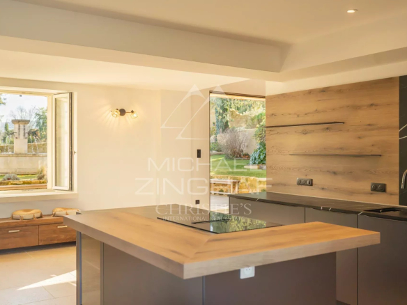 Interior of a modern kitchen with a wooden worktop and a window overlooking a garden.