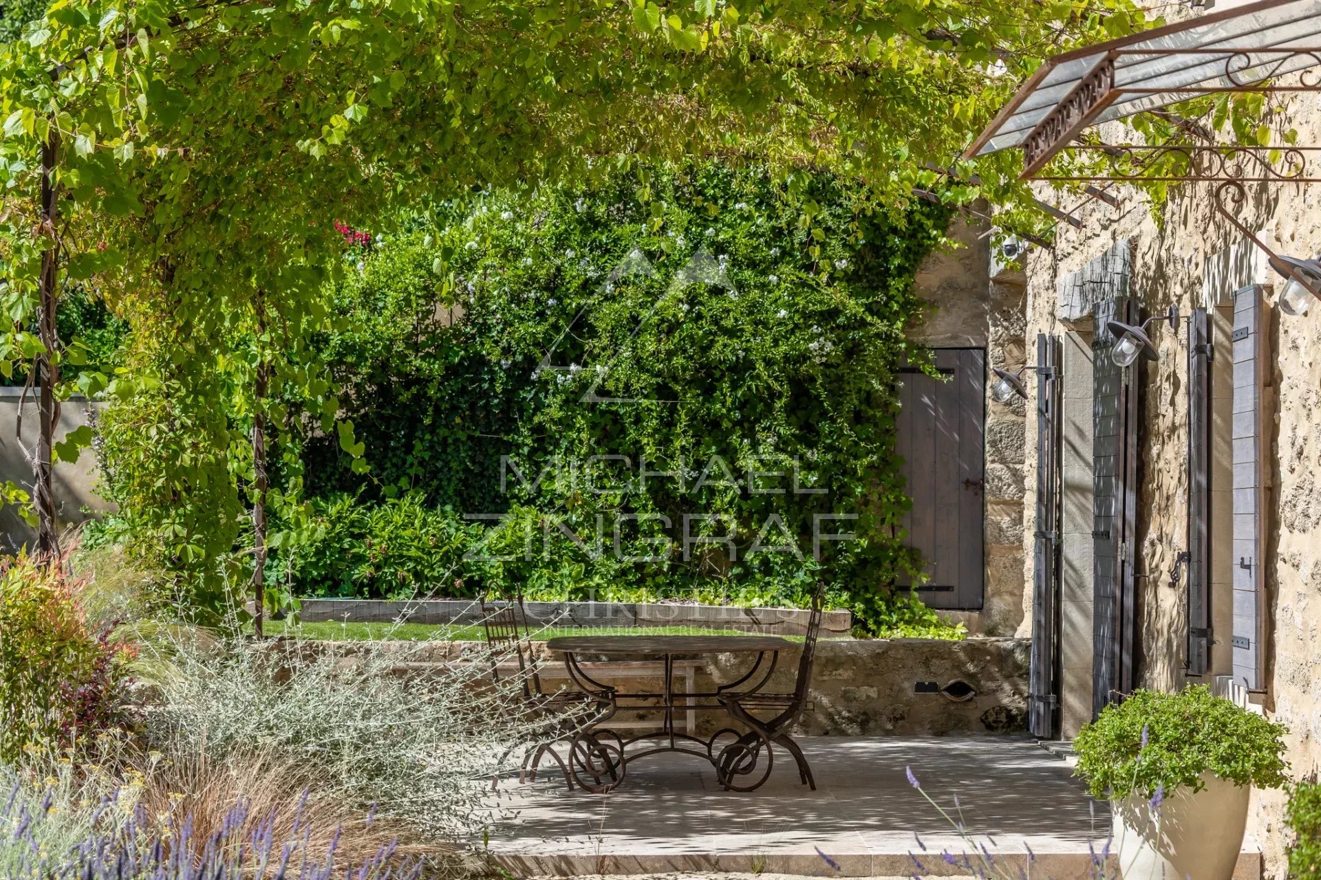 Terrace of a renovated farmhouse in Oppède Terrace of a renovated farmhouse with table and chairs, surrounded by greenery in Oppède.