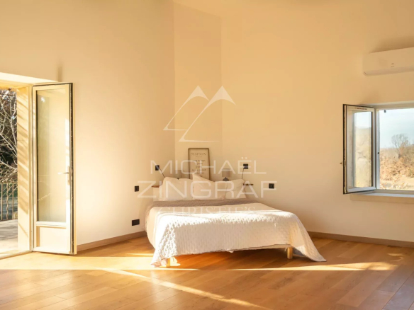 Bright room in a renovated farmhouse in Oppède with open windows and wooden parquet flooring.
