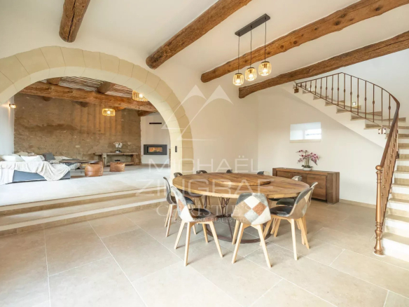 Interior of a renovated farmhouse with living room and dining room, exposed beams and staircase.