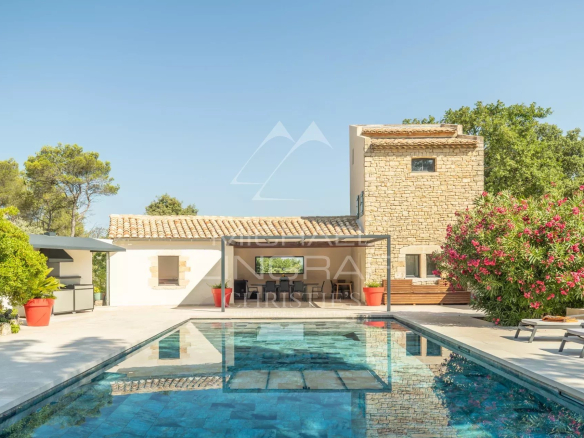 View of a stone house with swimming pool and outdoor space, surrounded by greenery, near L'Isle-sur-la-Sorgue.