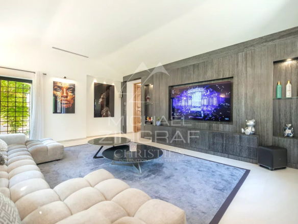 Interior of a modern living room with a large screen and artwork, bright lighting.