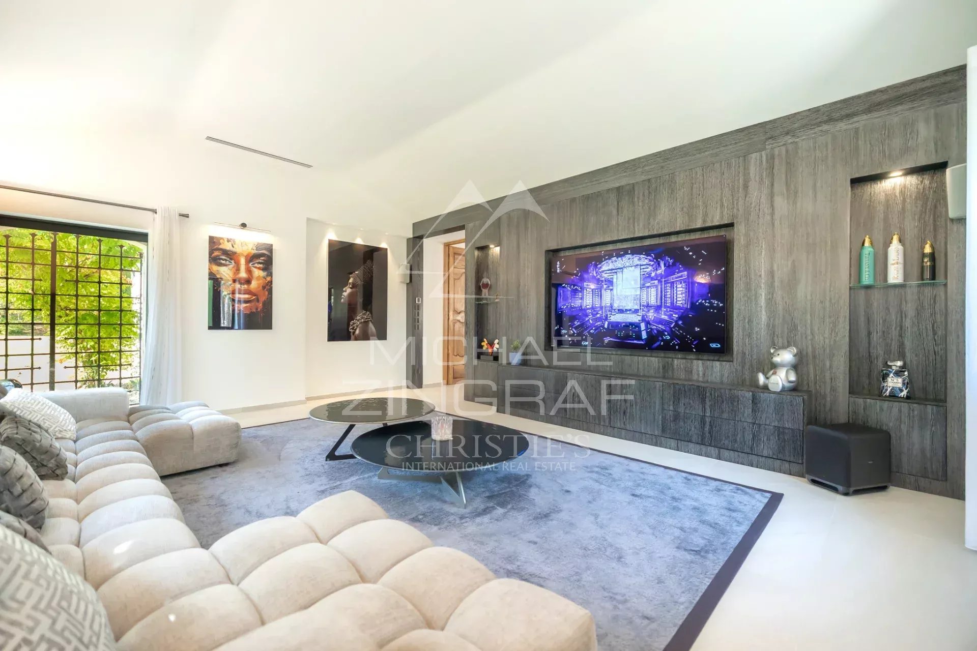 Modern living room in an exceptional property Interior of a modern living room with a large screen and artwork, bright lighting.