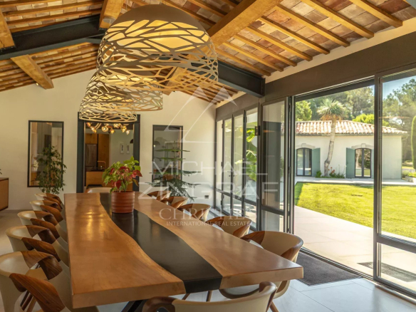 Interior of a renovated house with a large dining table and bay windows overlooking the garden.