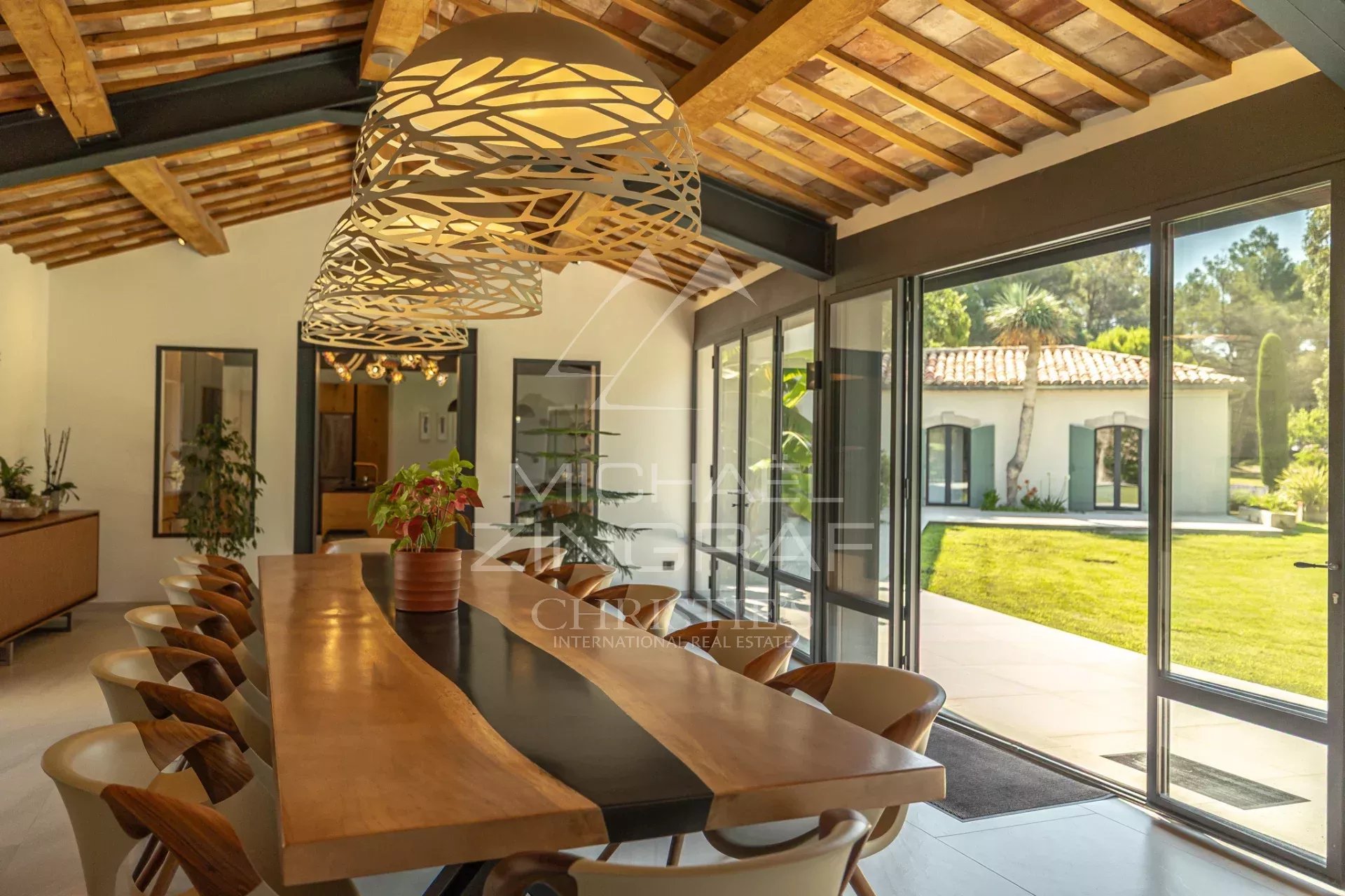 Modern interior of a Provençal house Interior of a renovated house with a large dining table and bay windows overlooking the garden.