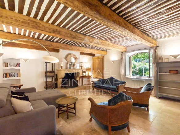 Intérieur d'un mas en pierre avec poutres apparentes et mobilier confortable.