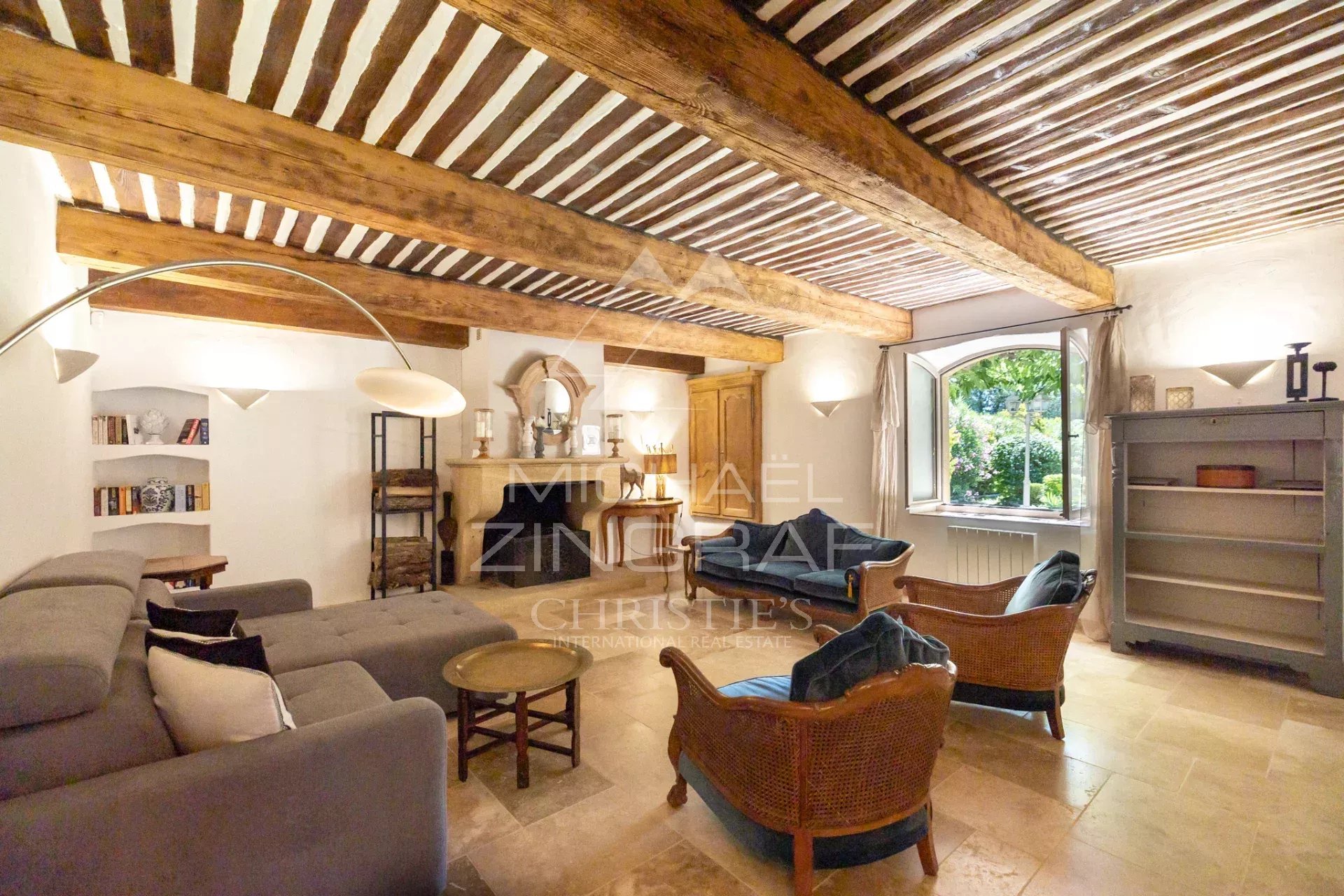 Intérieur d'un mas en pierre avec poutres apparentes et mobilier confortable.