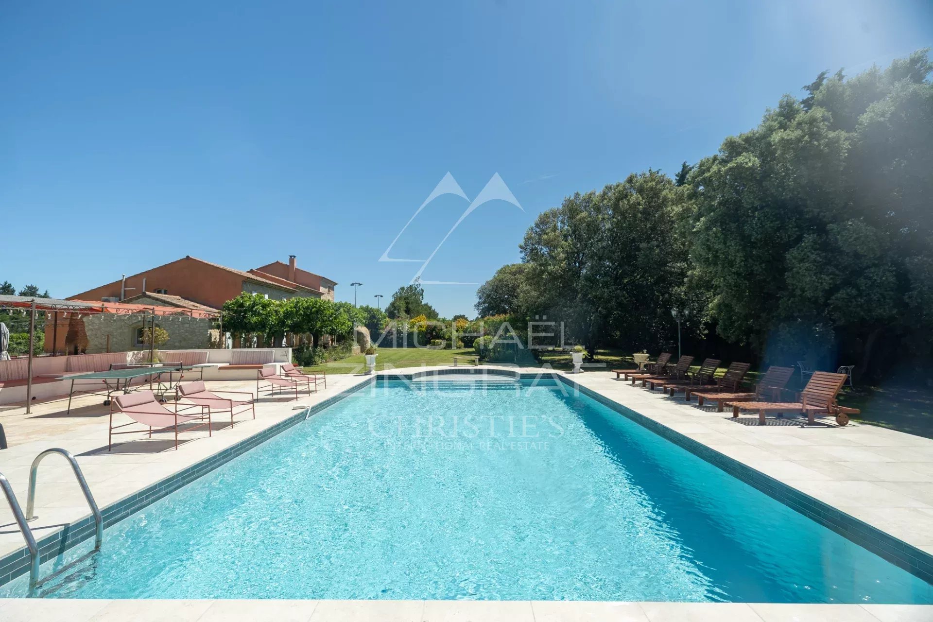 Piscine d'un mas en pierre avec chaises longues et jardins, Cavaillon