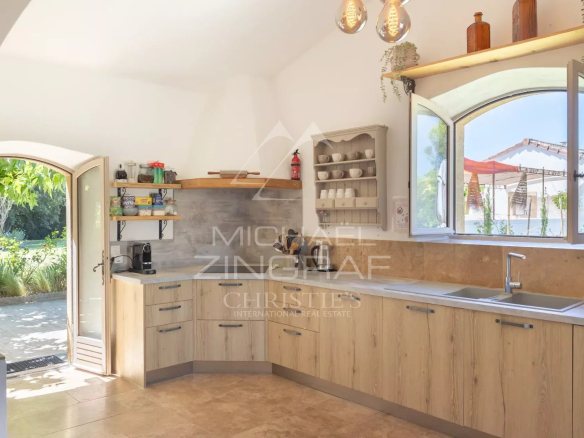 Cuisine ouverte dans un mas en pierre, avec vue sur le jardin extérieur.