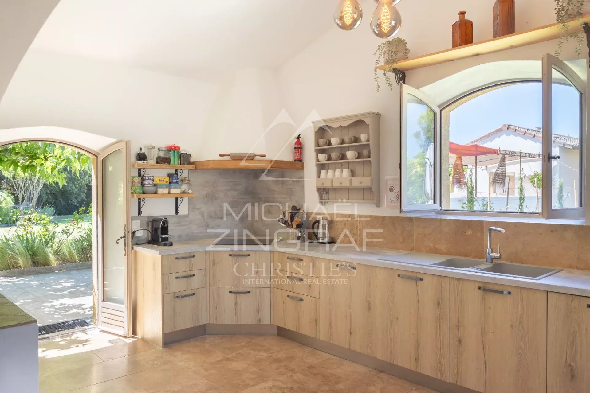Cuisine ouverte dans un mas en pierre, avec vue sur le jardin extérieur.
