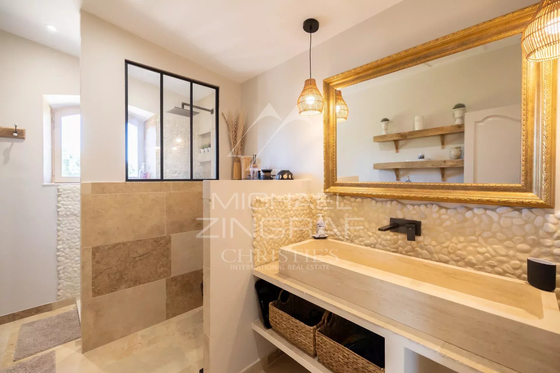 Salle de bain moderne avec lavabo en pierre et douche en verre, décorée de mosaïque et de lumière naturelle.