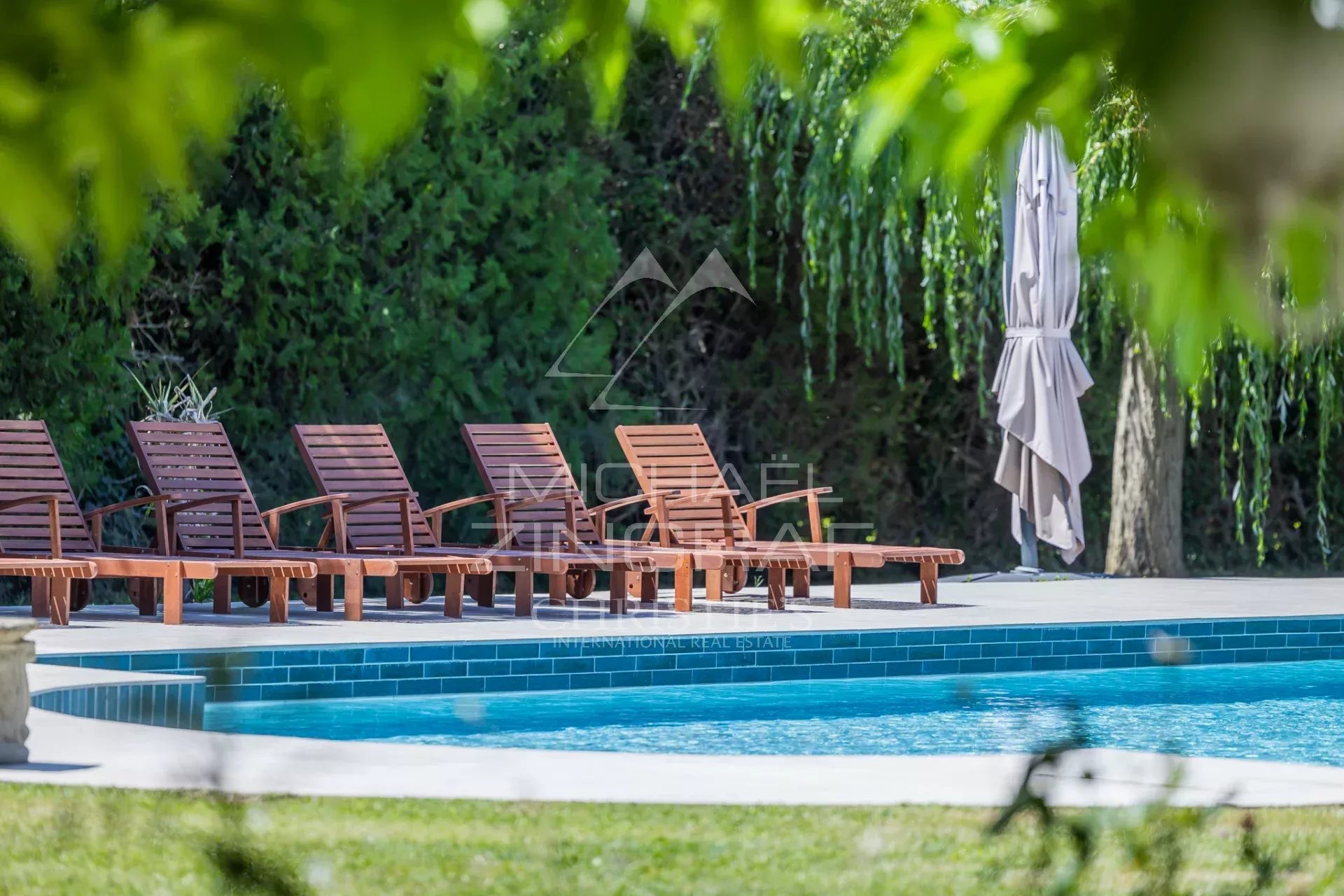 Terrasse avec chaises longues autour d'une piscine dans un mas en pierre