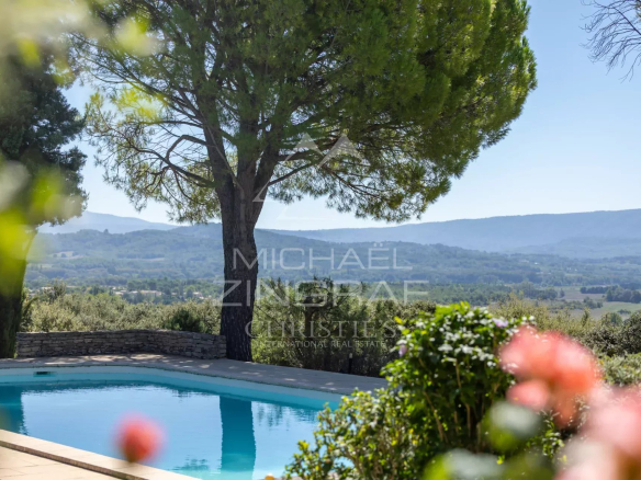 Vue d'une maison d'architecte avec piscine et paysage du Luberon en arrière-plan.
