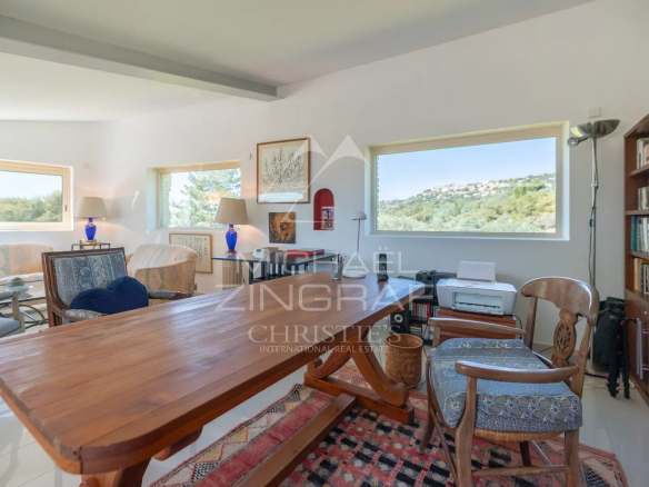 Intérieur d'une maison d'architecte à Gordes, avec mobilier moderne et grandes fenêtres offrant une vue sur la nature.