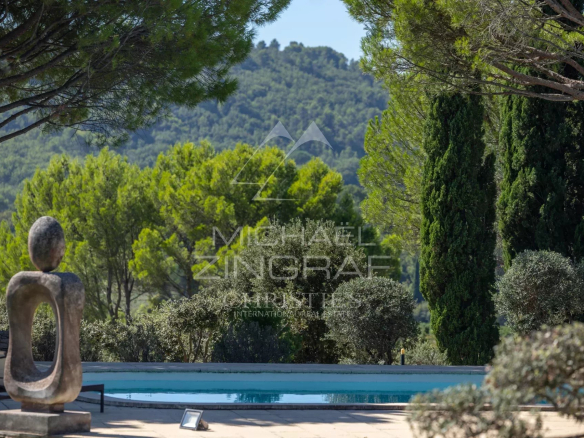 Vue d'une maison d'architecte avec piscine et sculptures, entourée de verdure à Gordes.