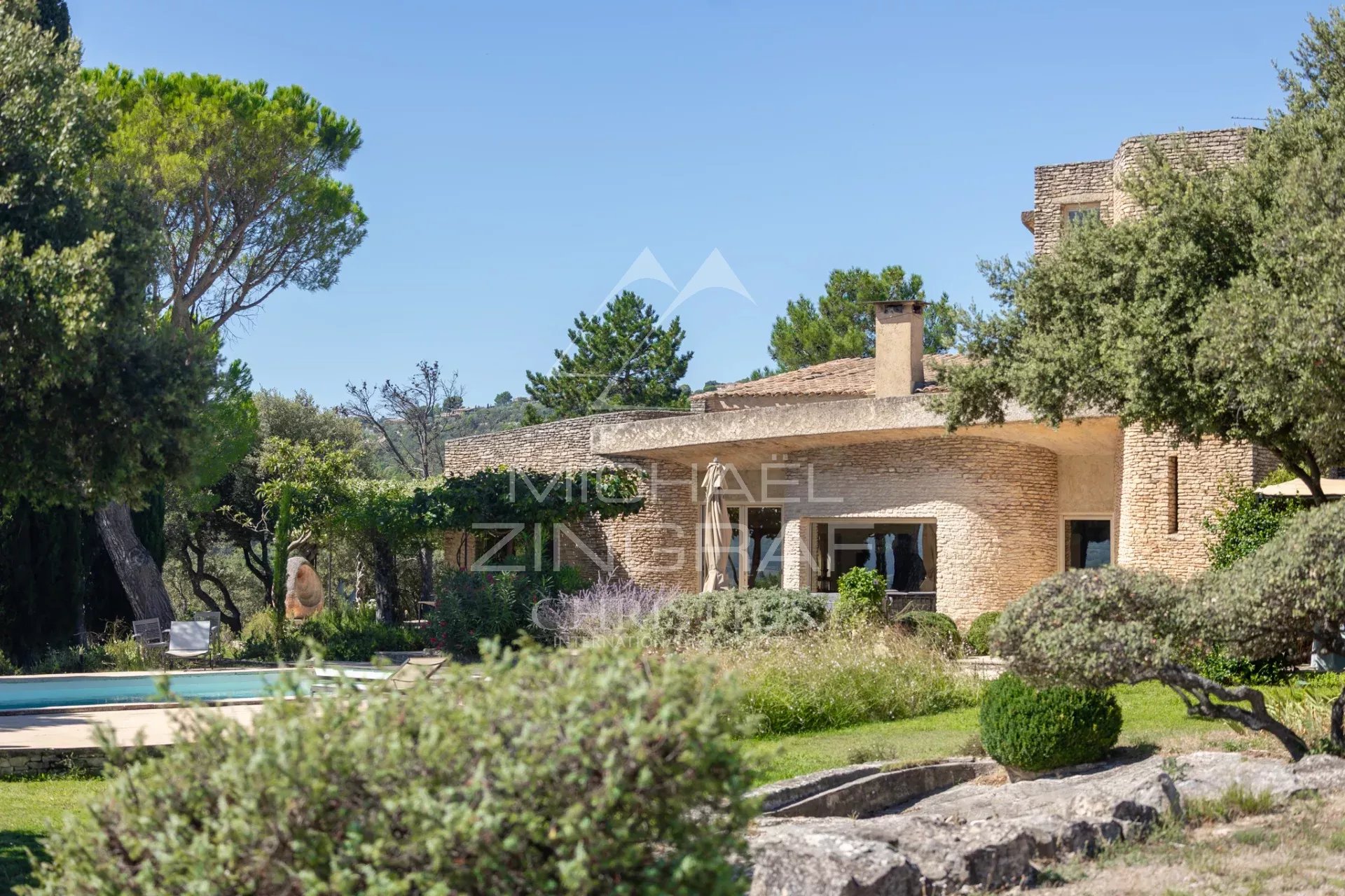 Maison d’architecte à Gordes Maison d'architecte à Gordes, entourée de verdure, avec piscine et éléments architecturaux distinctifs.