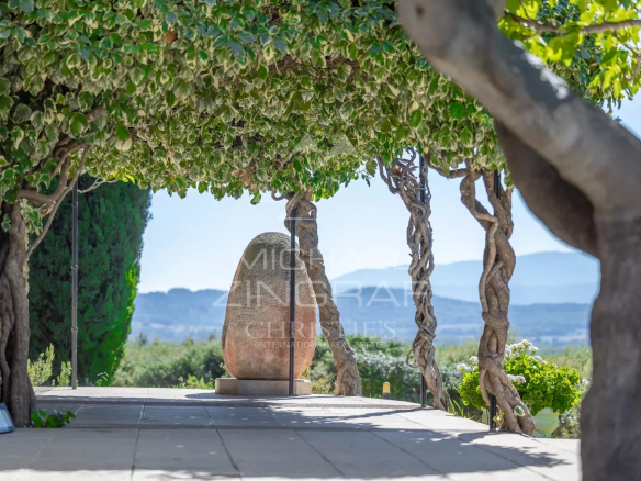 Terrasse d'une maison d'architecte à Gordes, avec vue sur le paysage du Luberon et sculpture en pierre.