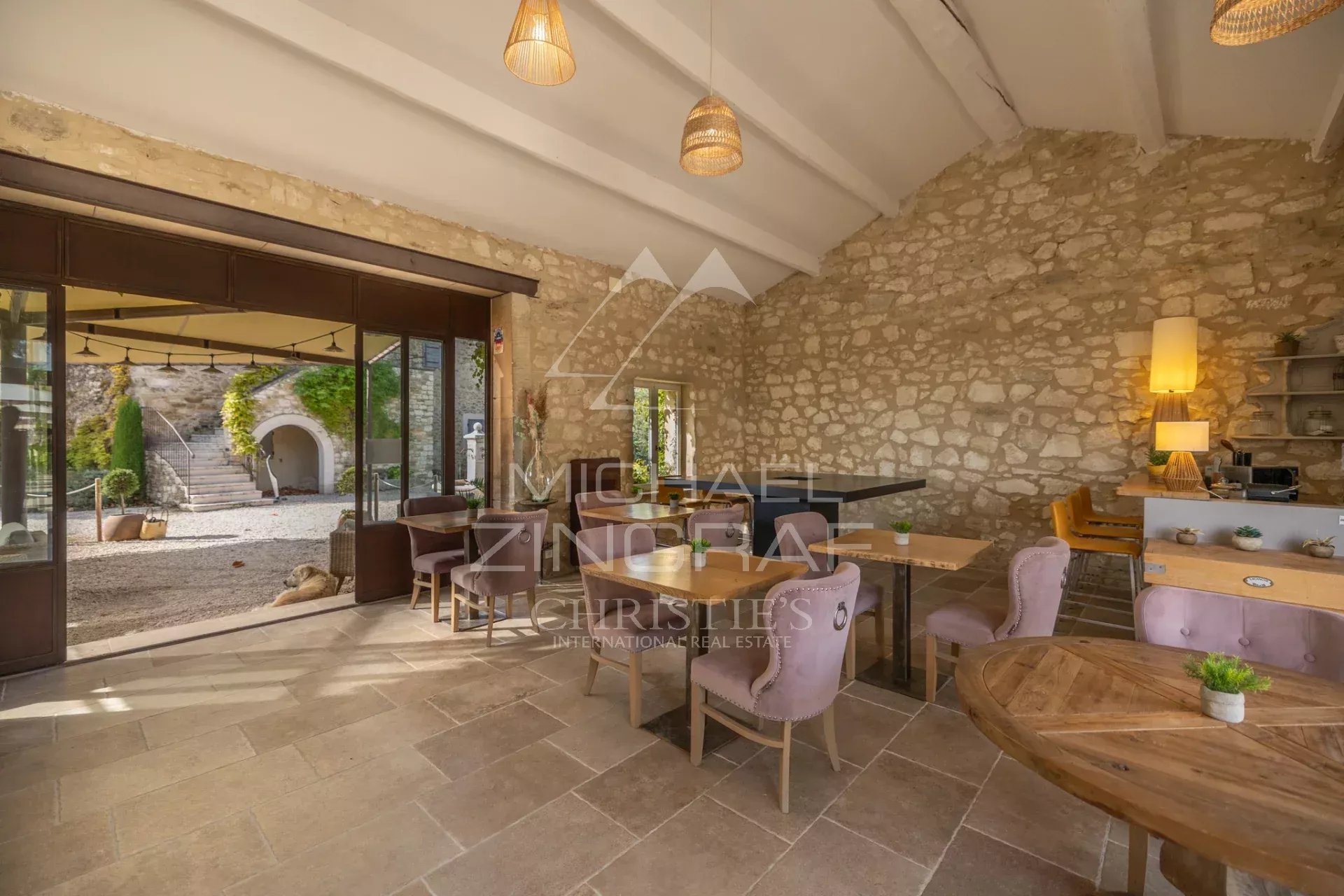 Interior of a Provencal farmhouse in Oppède Interior of a Provençal farmhouse with tables and chairs, stone walls, and large bay windows.