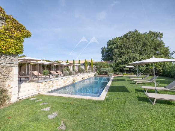 Provençal farmhouse with swimming pool and sun loungers, surrounded by greenery in Oppède.