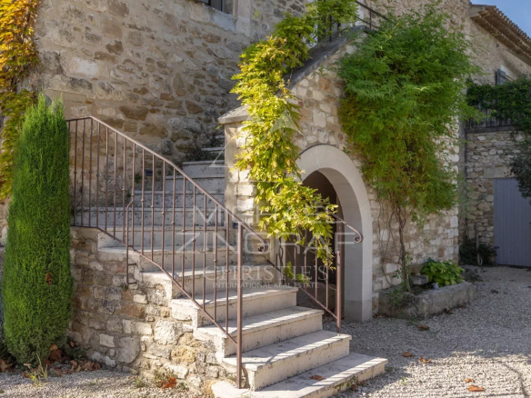 Stone staircase leading to a stone building with climbing plants in Oppède.
