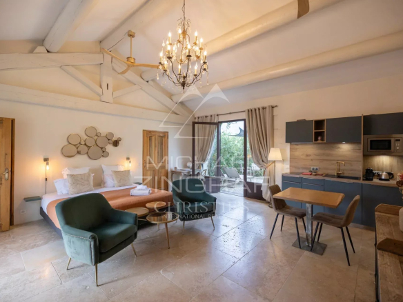 Interior of a cottage with bed, table and kitchenette, decorated in a Provençal style.